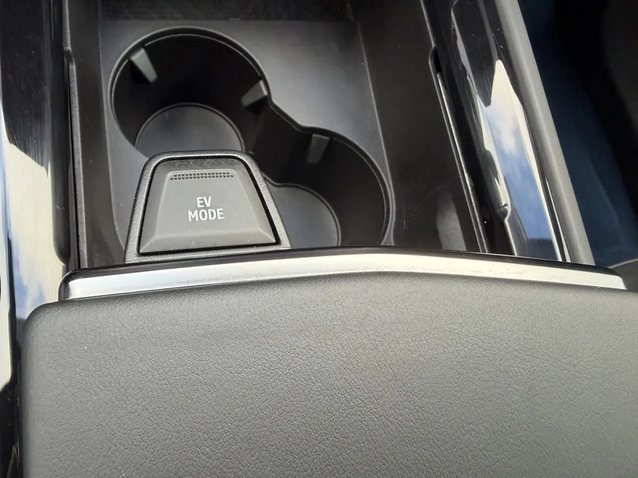 Gros plan sur la console centrale noire avec bouton EV MODE et porte-gobelets du Renault Rafale Summit Blue hybride rechargeable.