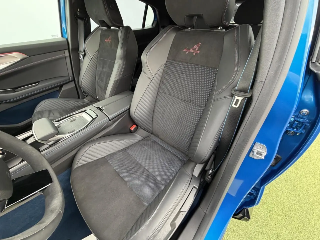 Vue intérieure côté conducteur du Renault Rafale Summit Blue 2025, sièges sport en Alcantara avec logo Alpine rouge brodé.