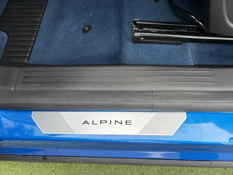 Gros plan sur la plaque de seuil de porte "ALPINE" sur un Renault Rafale Summit Blue, intérieur avec moquette bleue.