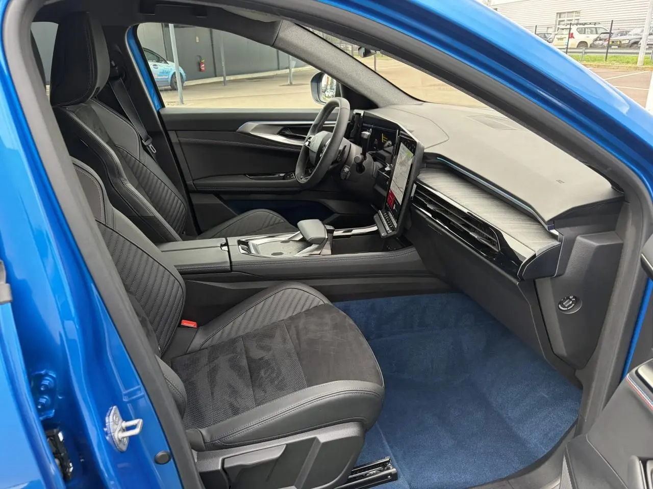 Vue intérieure côté conducteur du Renault Rafale Summit Blue 2025, avec sièges sport noirs et tableau de bord moderne.