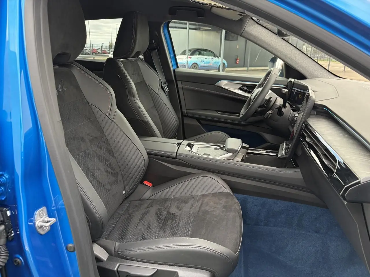 Vue intérieure côté conducteur de la Renault Rafale Summit Blue 2025, sièges sport en Alcantara noir avec surpiqûres rouges.