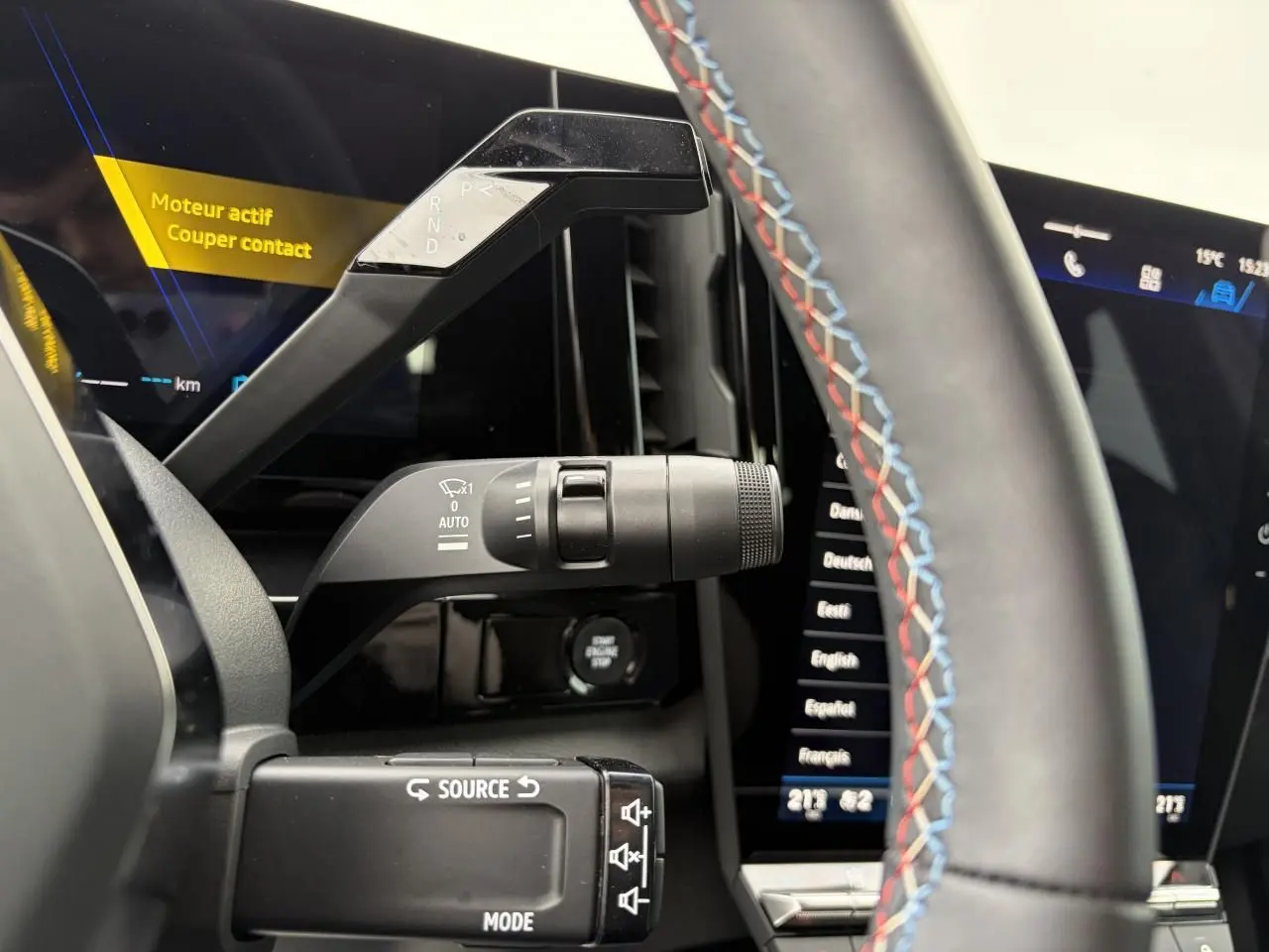 Détail intérieur du levier de vitesses et commandes au volant avec surpiqûres tricolores dans une Renault Rafale Summit Blue.