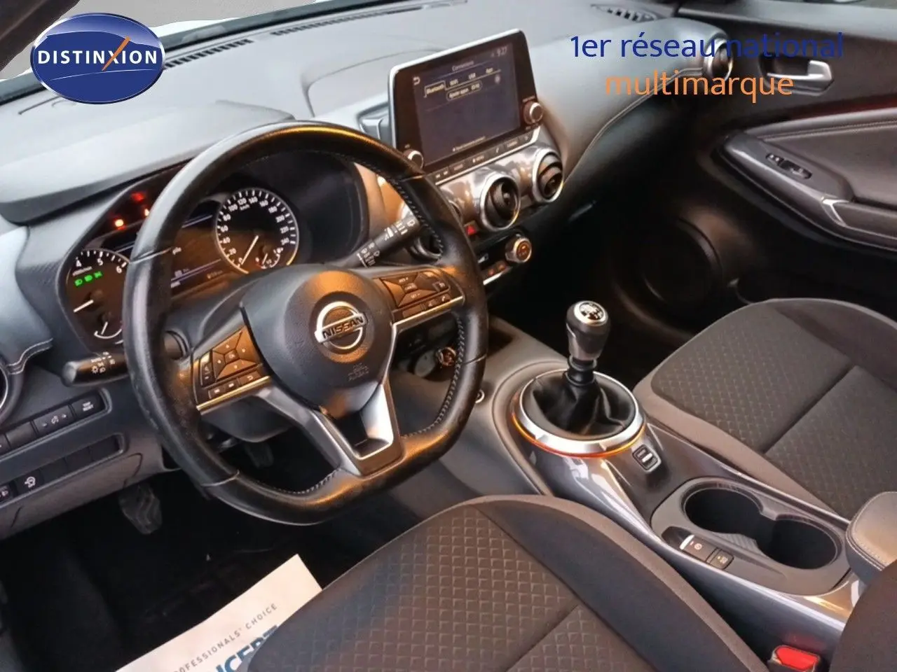 Vue intérieure côté conducteur du Nissan Juke 2020, tableau de bord noir avec volant cuir et levier de vitesse manuel.