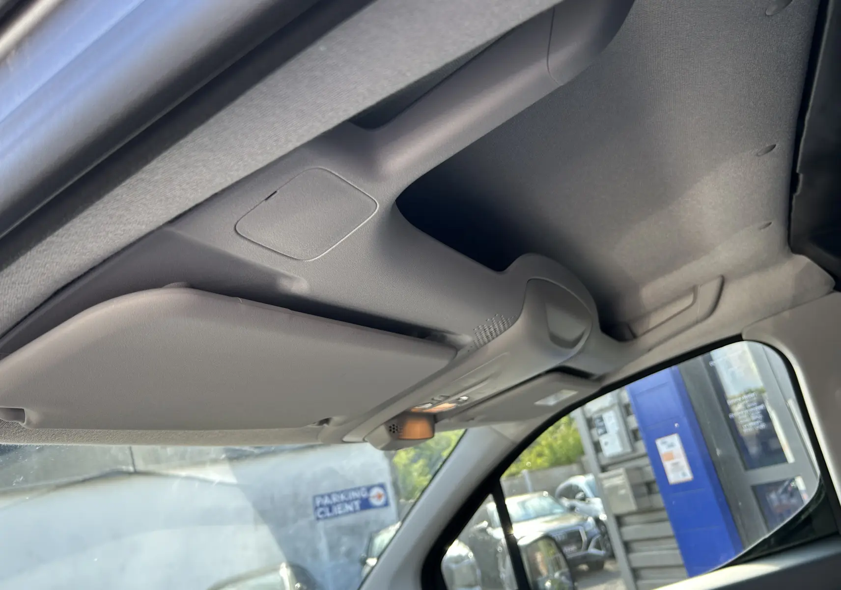 Vue intérieure en plongée du pare-soleil côté conducteur du Dangel Partner 4x4, avec toit gris et vitre latérale visible.