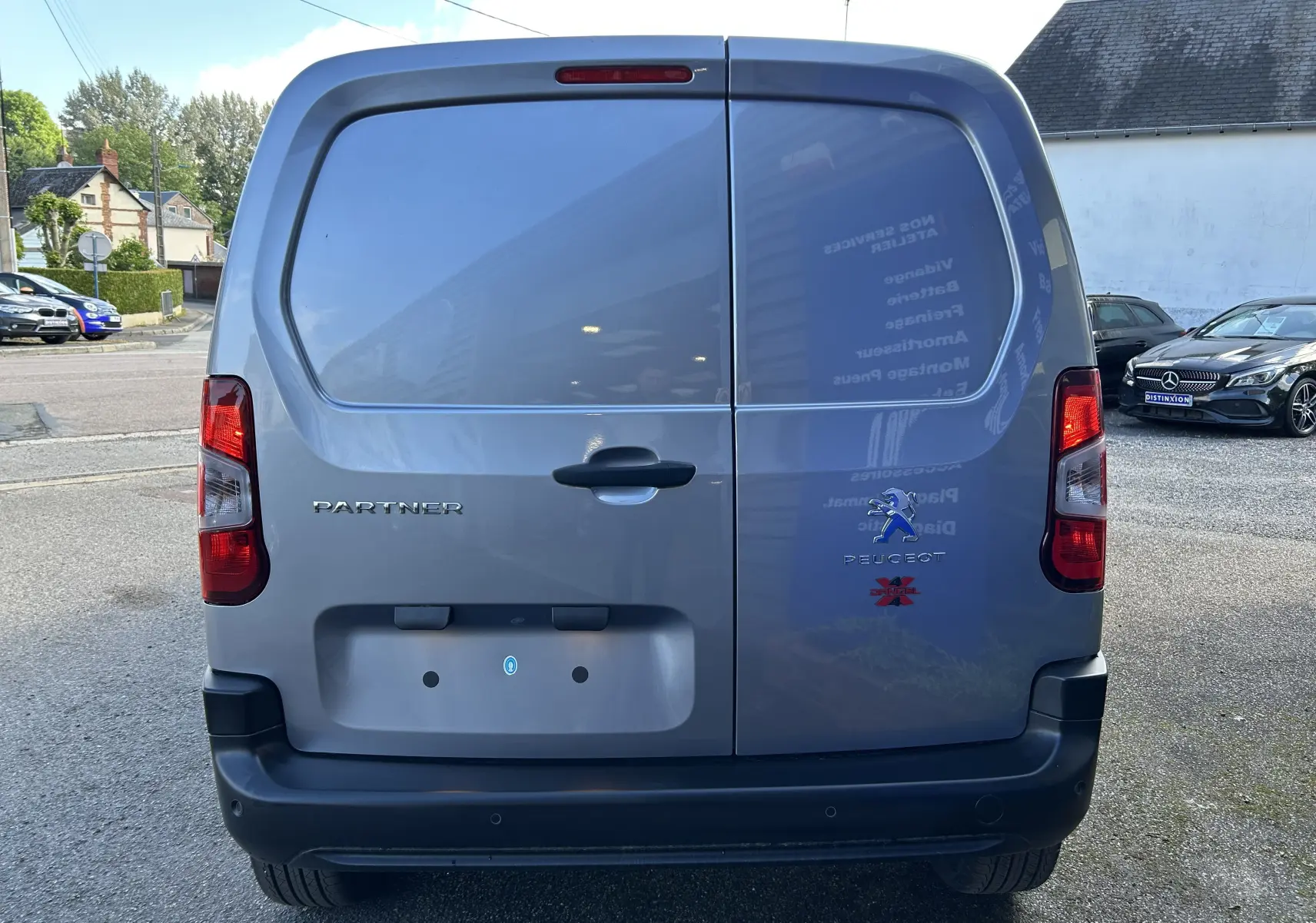 Vue arrière d’un Peugeot Partner Dangel 4x4 gris Artense avec portes battantes et logos visibles.