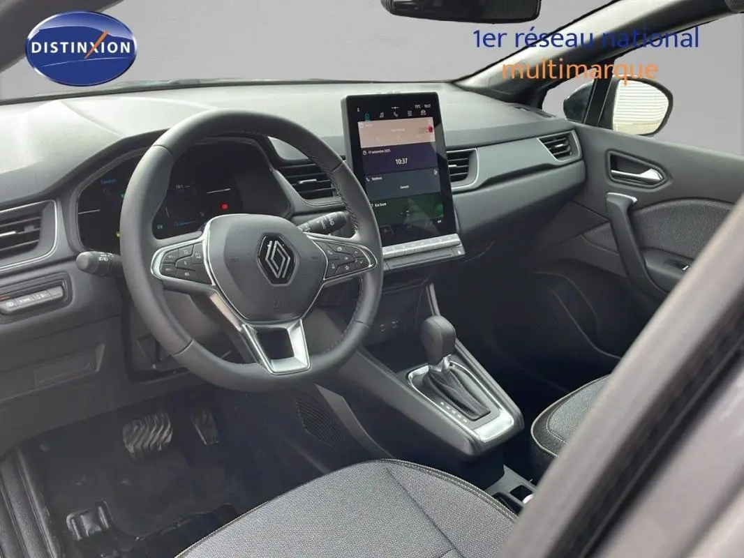 Vue intérieure côté conducteur du Renault Captur gris 2025, volant cuir, écran tactile vertical et boîte automatique.