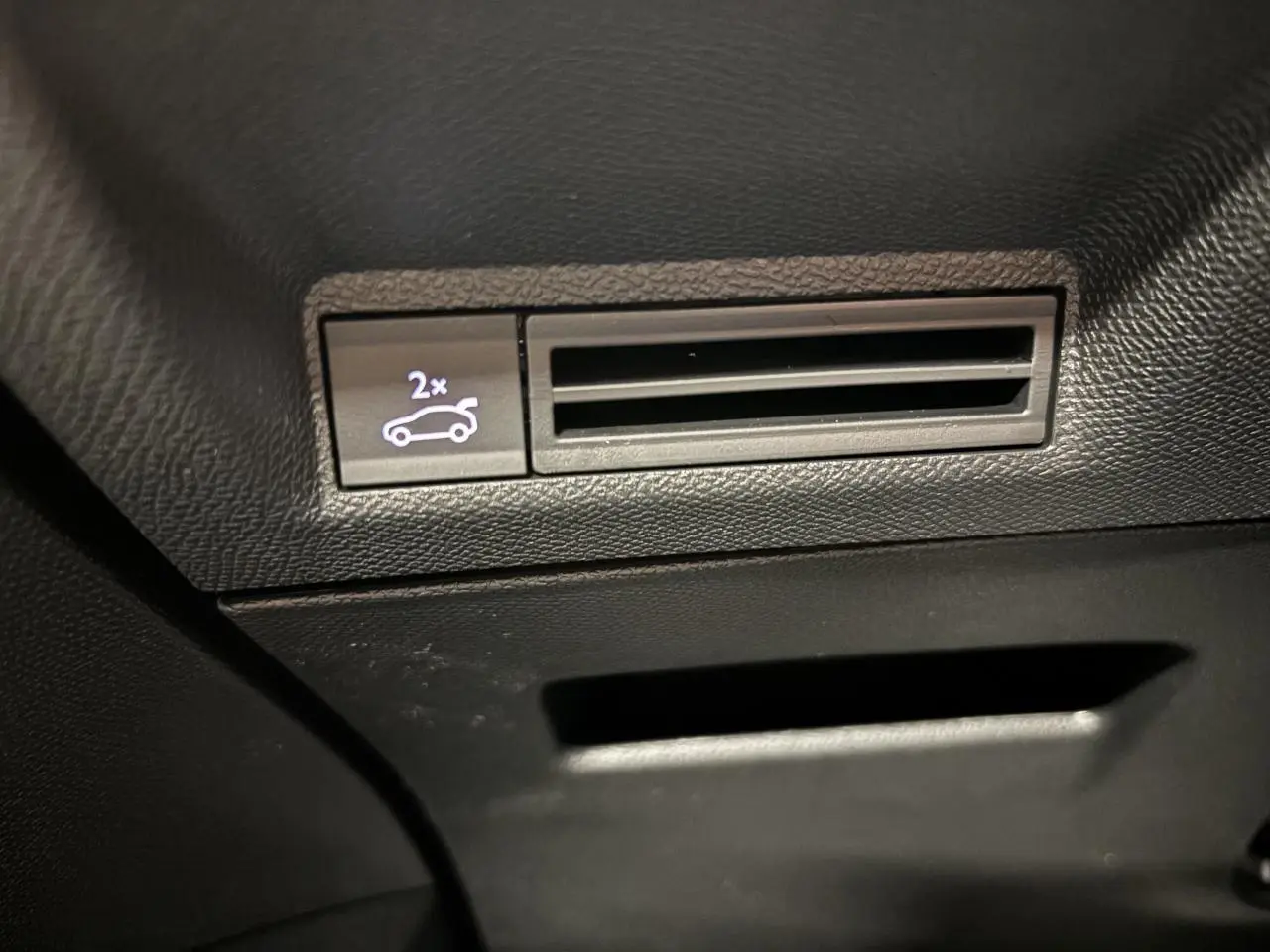 Gros plan sur le bouton d'ouverture du hayon électrique dans l'habitacle noir du Peugeot 3008 Gris Artense.
