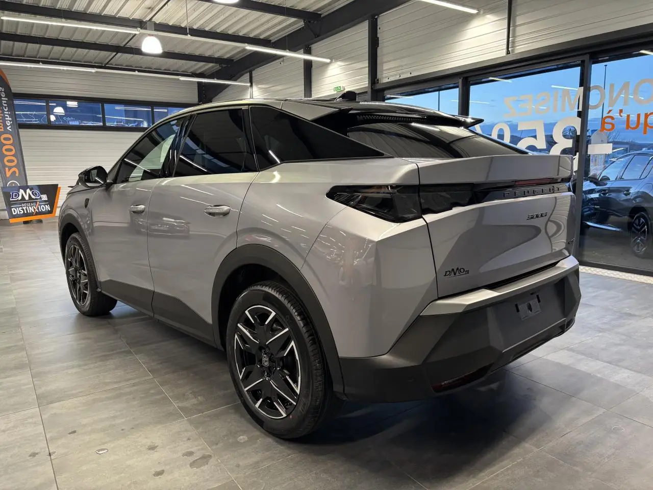 Vue 3/4 arrière droit du Peugeot 3008 gris Artense avec toit noir et jantes alliage 19 pouces en showroom.