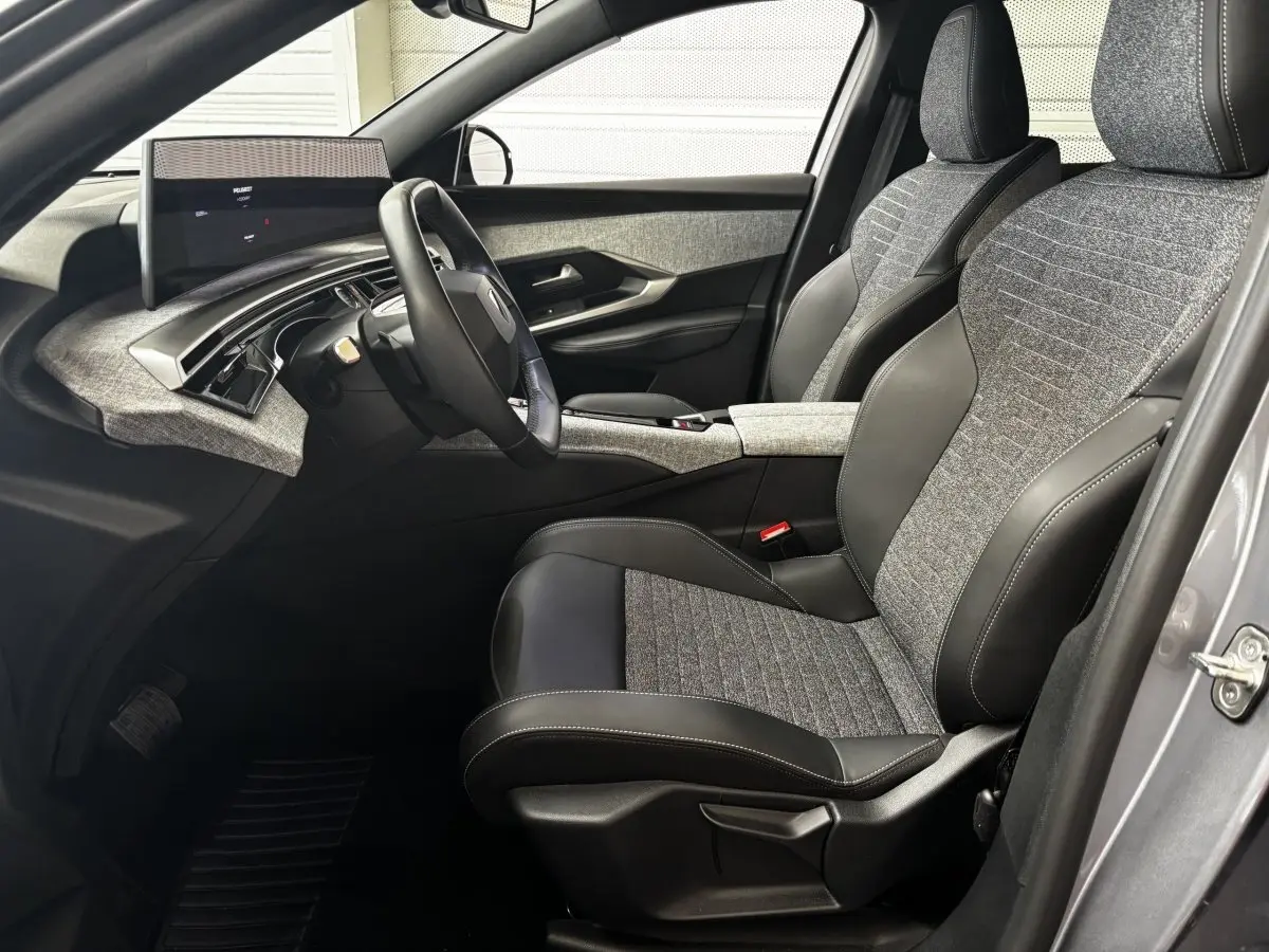 Vue intérieure côté conducteur du Peugeot 3008 gris clair 2025, sièges tissu et cuir, tableau de bord moderne avec écran tactile.