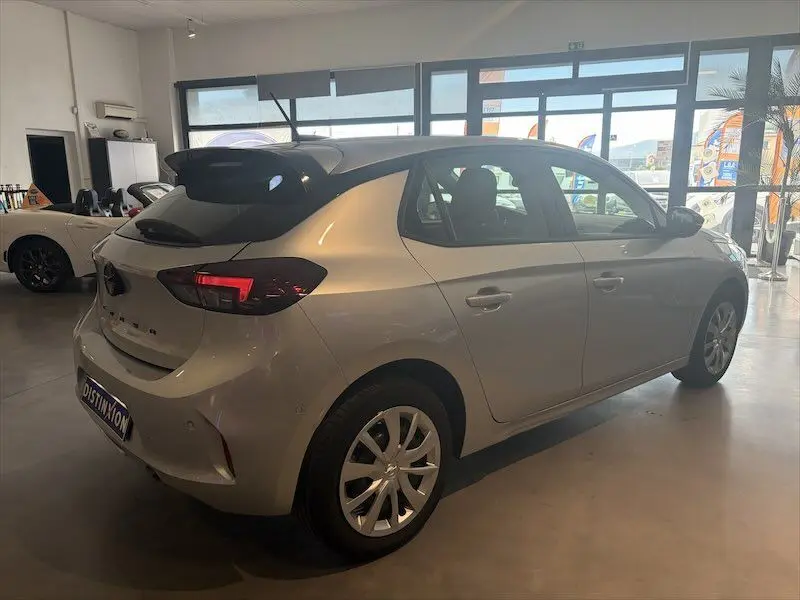 Opel Corsa gris 2025 vue 3/4 arrière droit en intérieur, avec feux arrière allumés et jantes alliage.