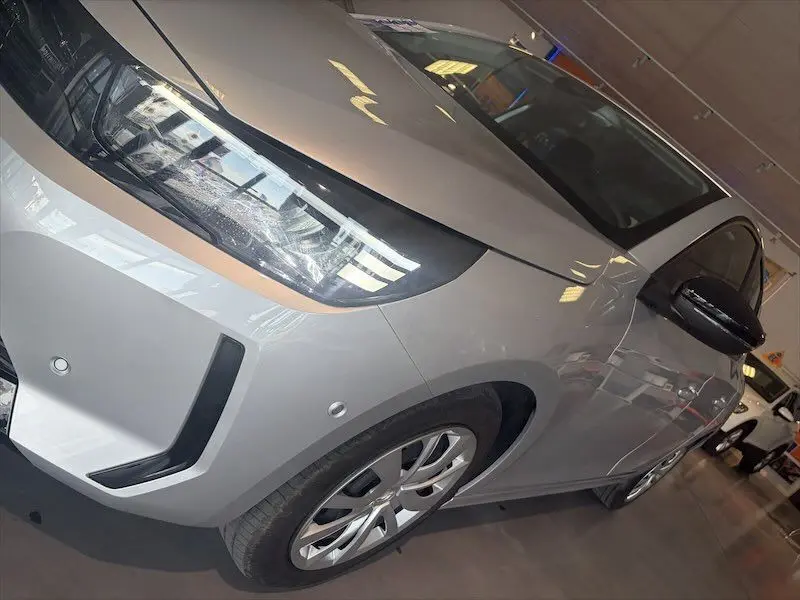 Vue 3/4 avant droit d'une Opel Corsa 1.2 Turbo 100 Edition gris clair avec phares LED et jantes alliage.