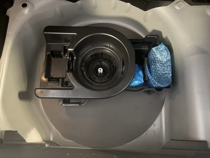 Vue plongeante sur le rangement de roue de secours d'une Opel Corsa 2025 gris, avec kit de réparation et outils emballés.