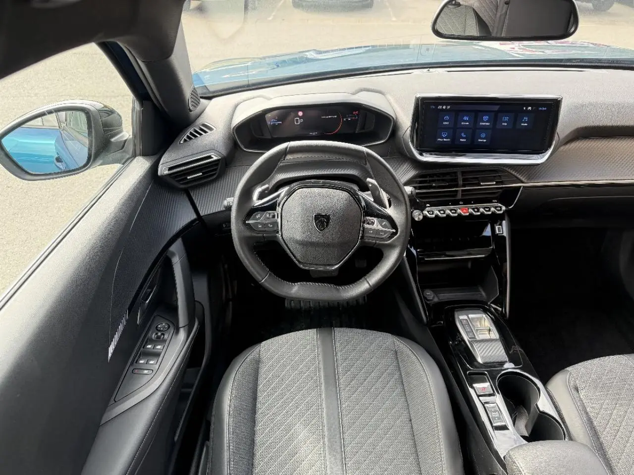Vue intérieure du poste de conduite du Peugeot 2008 2025 bleu obsession, avec volant compact et écran tactile central.