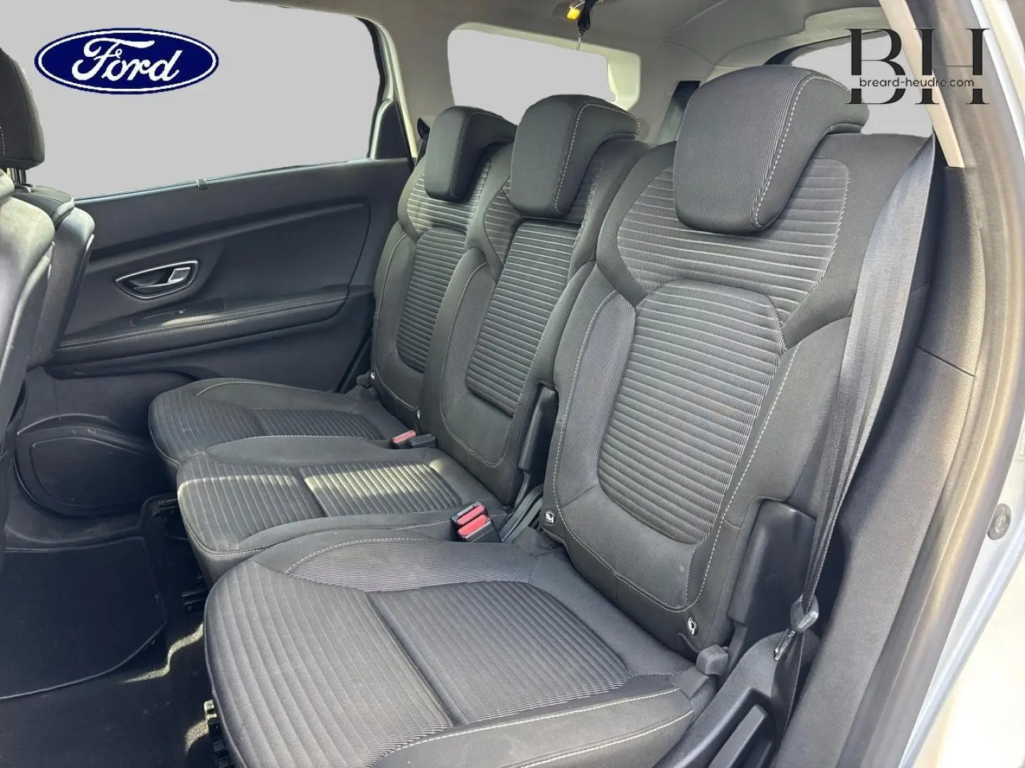 Vue latérale des sièges arrière en tissu carbone foncé d'un Renault Grand Scenic gris platine, montrant trois places avec appuie-têtes.