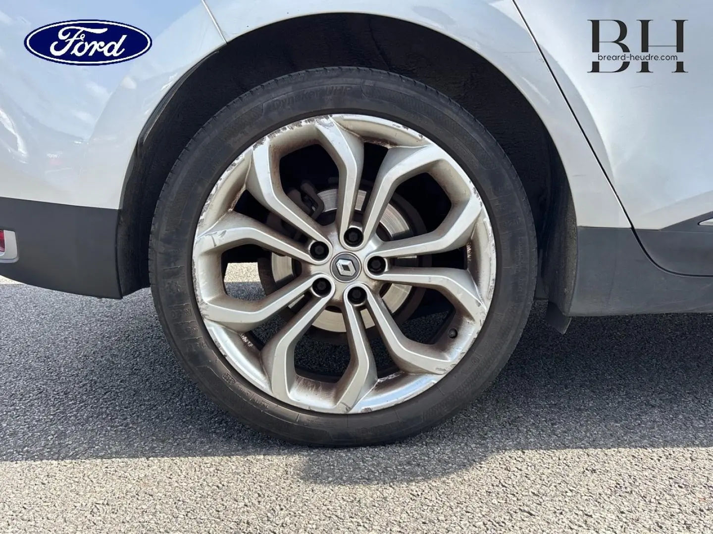 Gros plan sur la roue arrière droite d'un Renault Grand Scénic gris platine avec jante alliage à motif moderne.