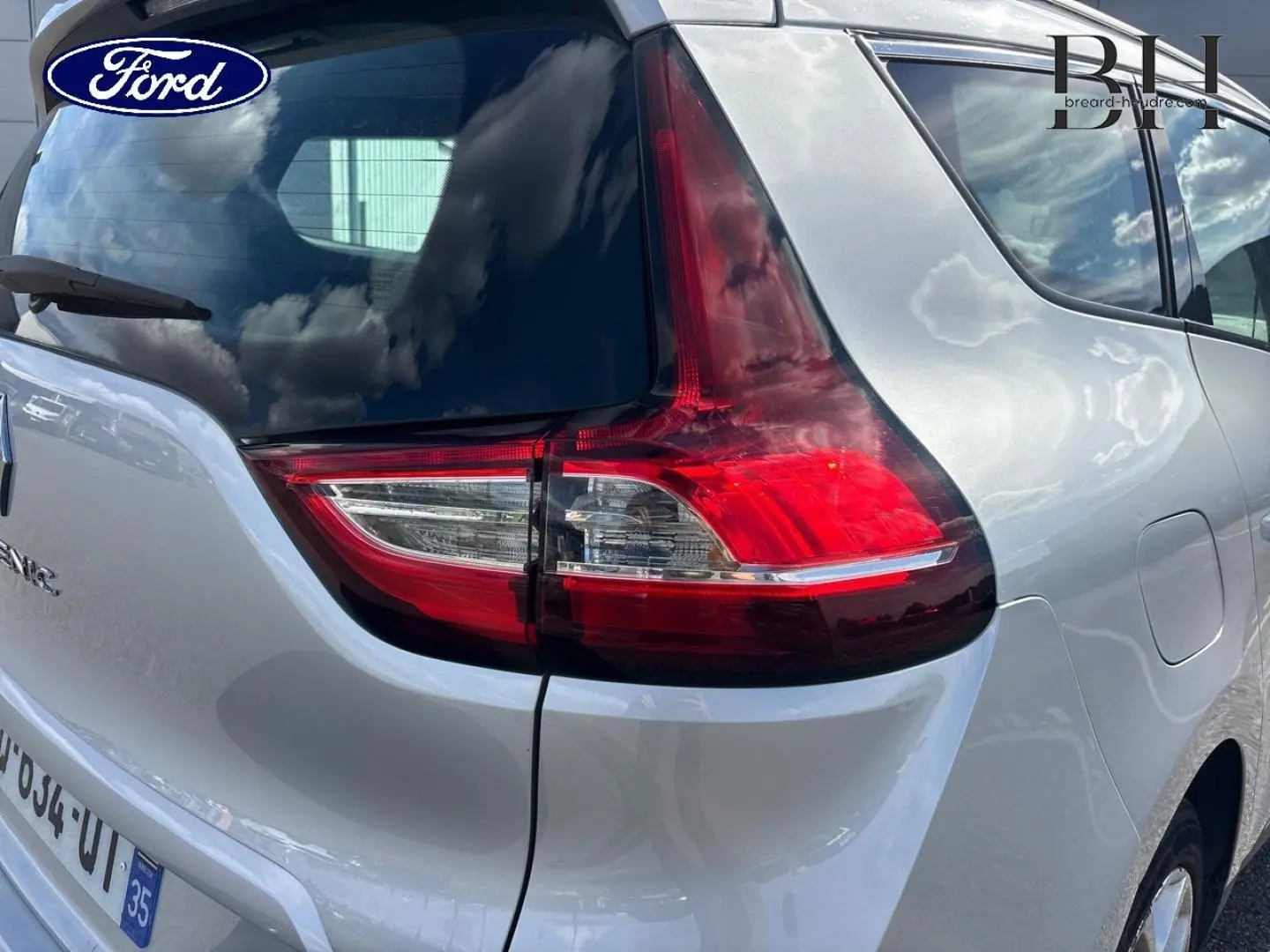 Vue arrière droite du Renault Grand Scénic gris platine, mettant en valeur le feu arrière et la lunette teintée.