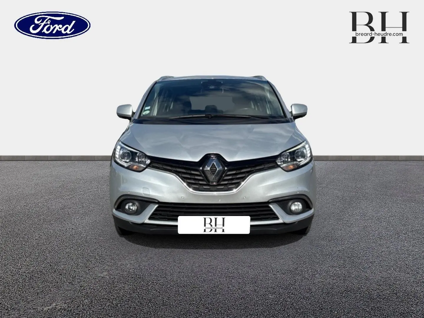 Renault Grand Scenic gris platine vue de face, avec calandre noire et phares LED allumés sur fond neutre.