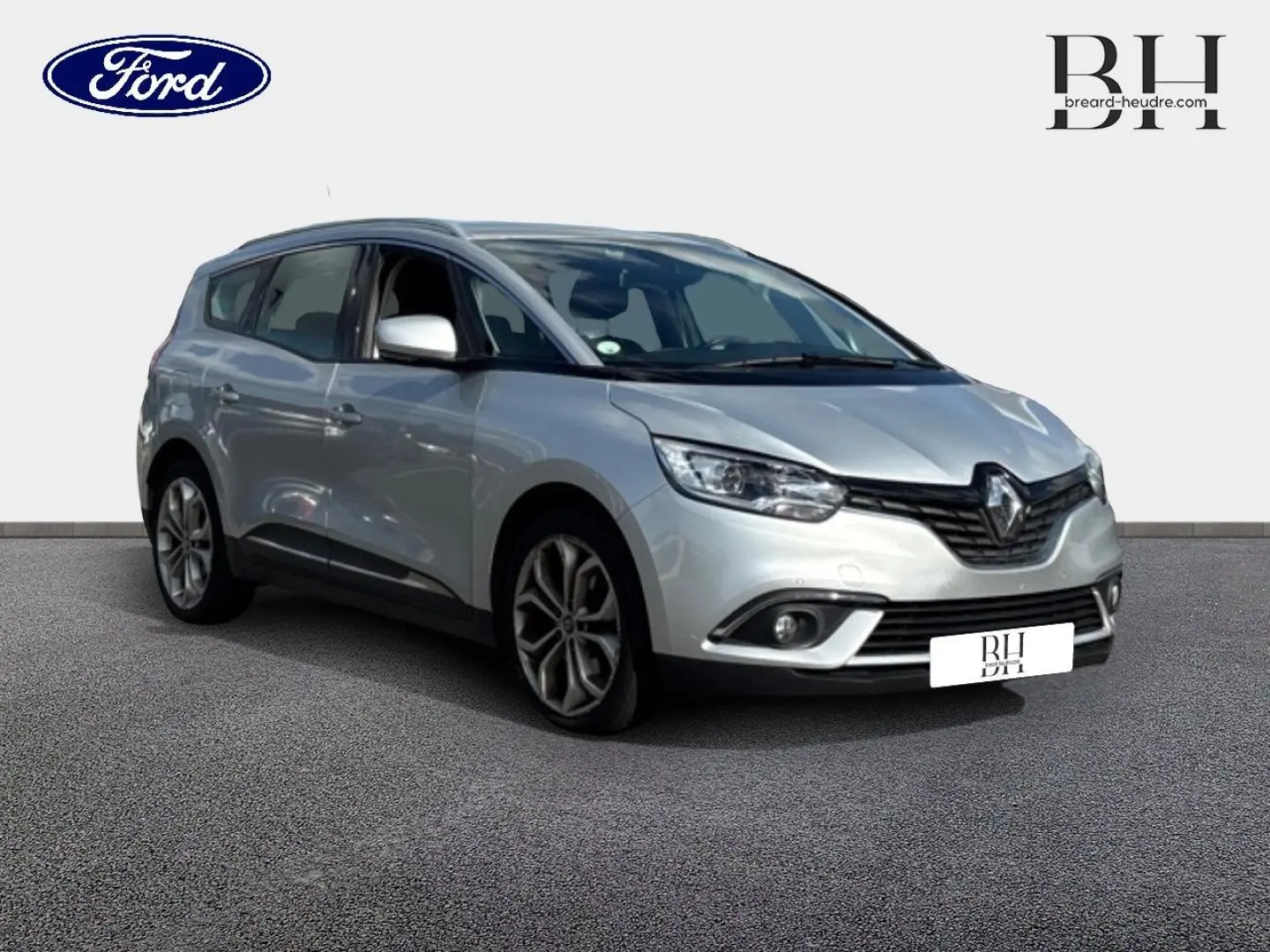 Renault Grand Scenic gris platine en 3/4 avant droit, avec jantes alliage et feux LED visibles.
