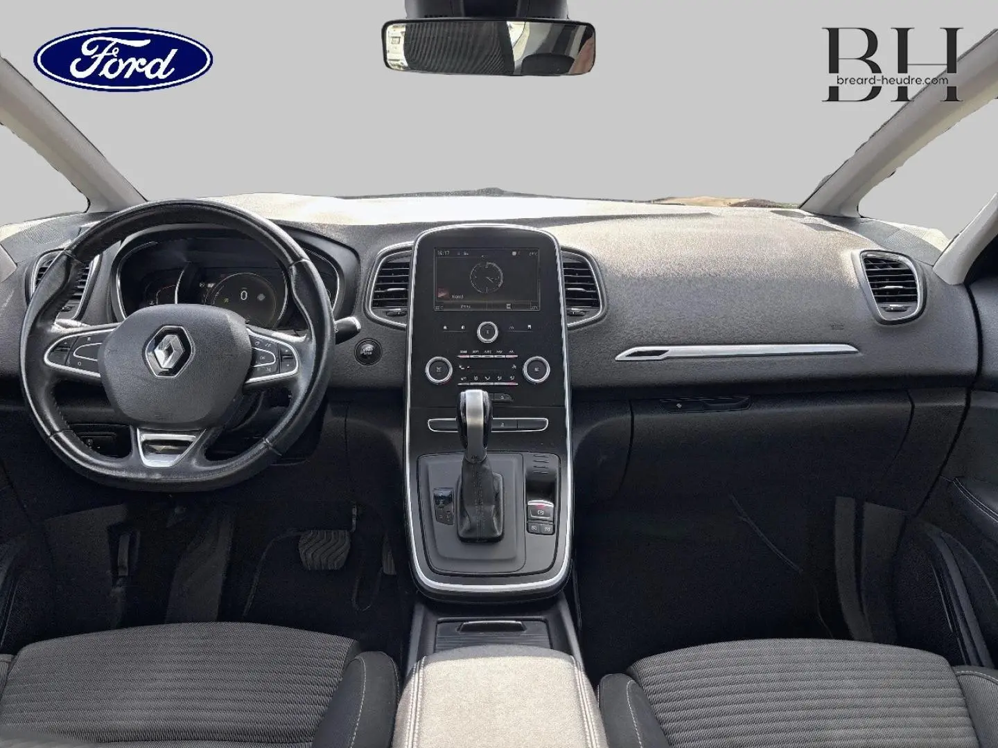 Vue intérieure avant du tableau de bord et console centrale du Renault Grand Scenic gris avec volant cuir et écran tactile.