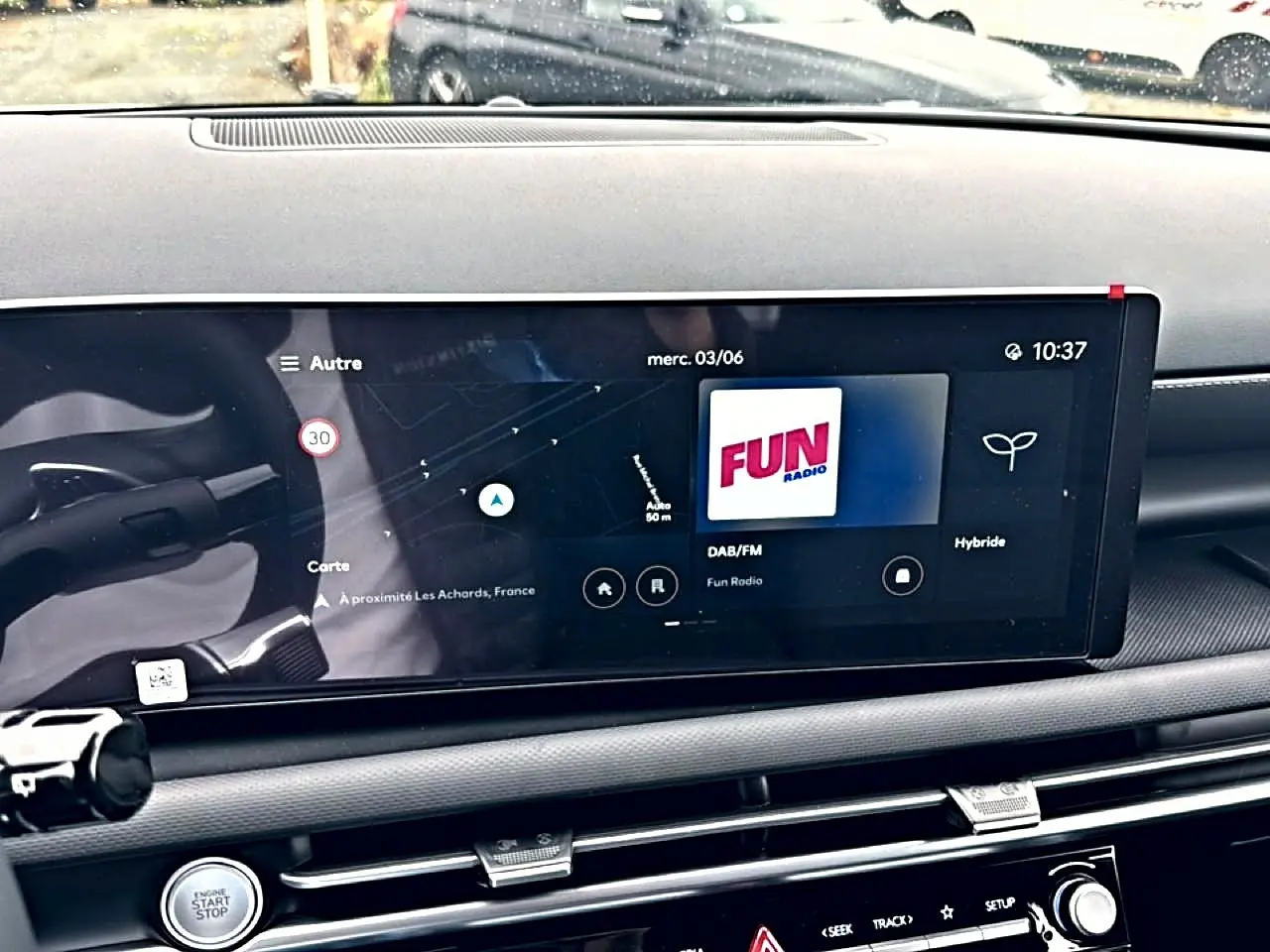 Vue rapprochée de l'écran tactile central du tableau de bord du Hyundai Tucson blanc, affichant la radio et la navigation.