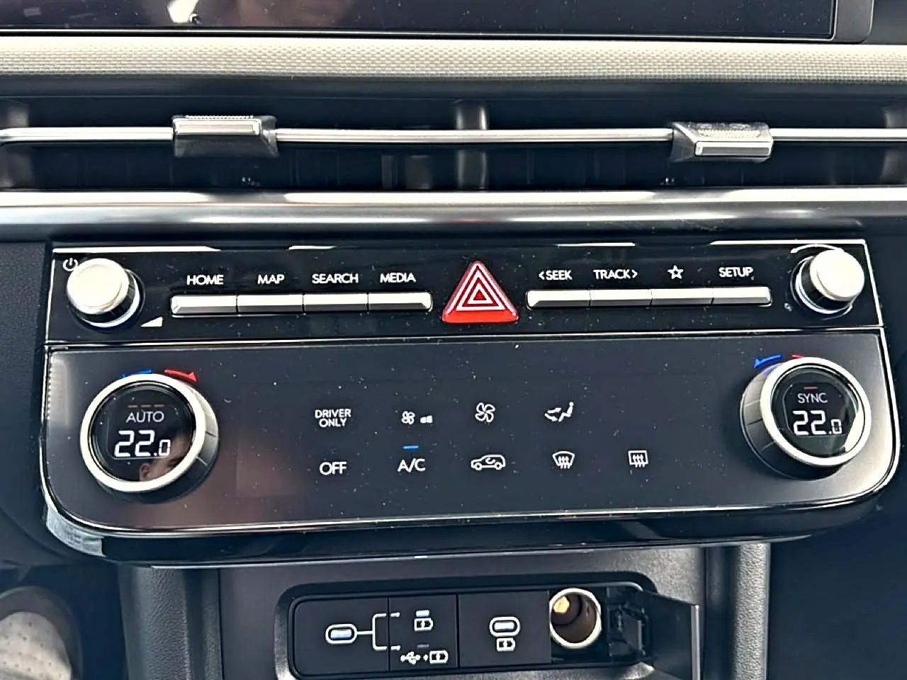 Vue rapprochée de la console centrale du Hyundai Tucson 2026 hybride, avec commandes climatisation digitale à 22°C.