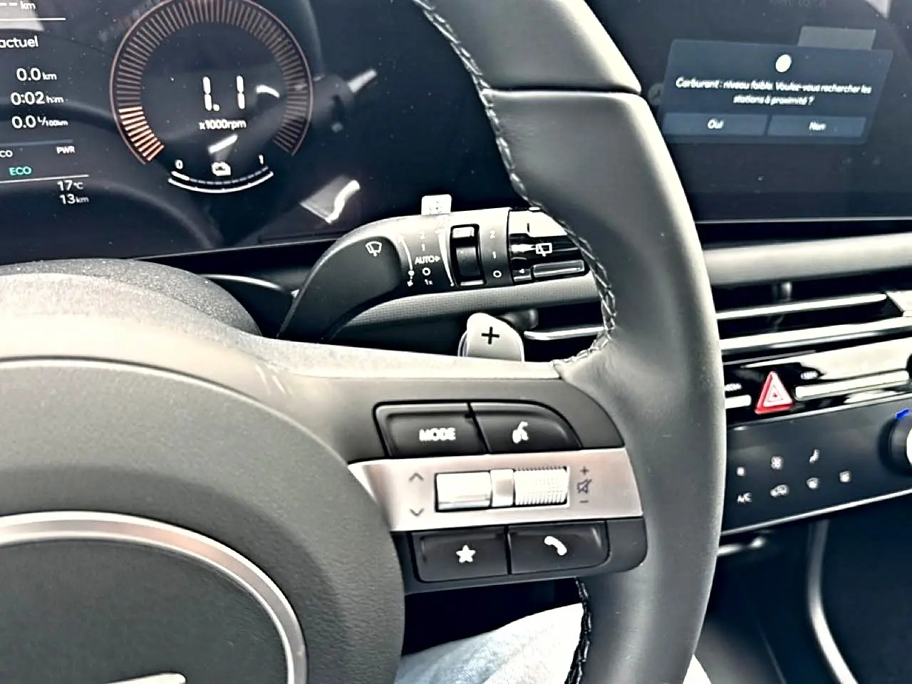 Vue rapprochée du volant cuir multifonction noir du Hyundai Tucson 2026 avec commandes audio et écran digital en arrière-plan.