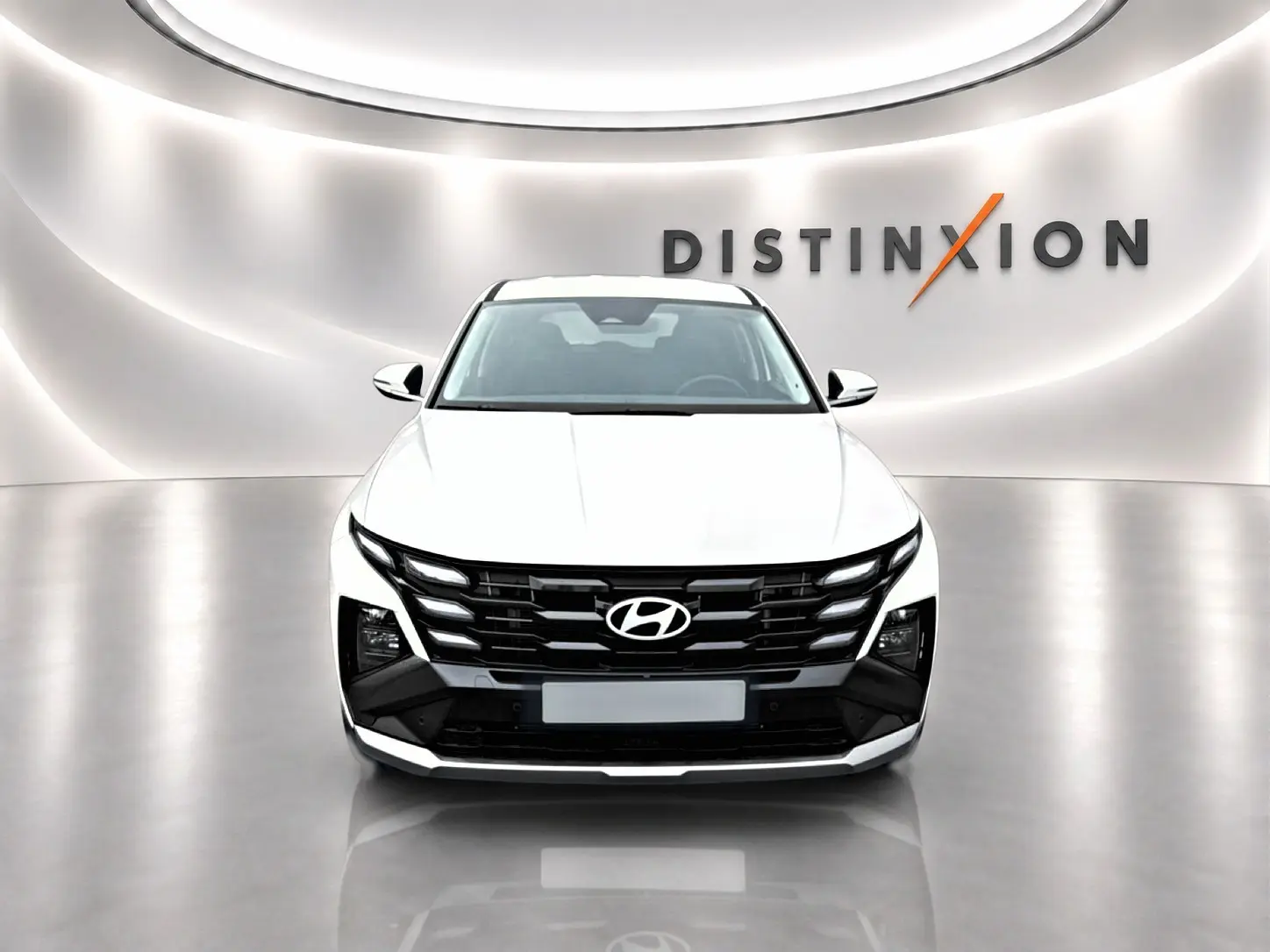 Vue frontale du Hyundai Tucson blanc 2026 avec calandre noire et éclairage LED distinctif en showroom.
