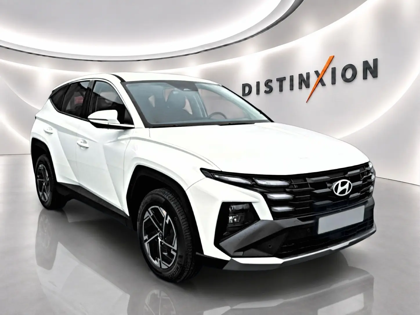 Hyundai Tucson blanc 2026 en 3/4 avant droit, avec calandre noire et jantes alliage 17 pouces distinctives.