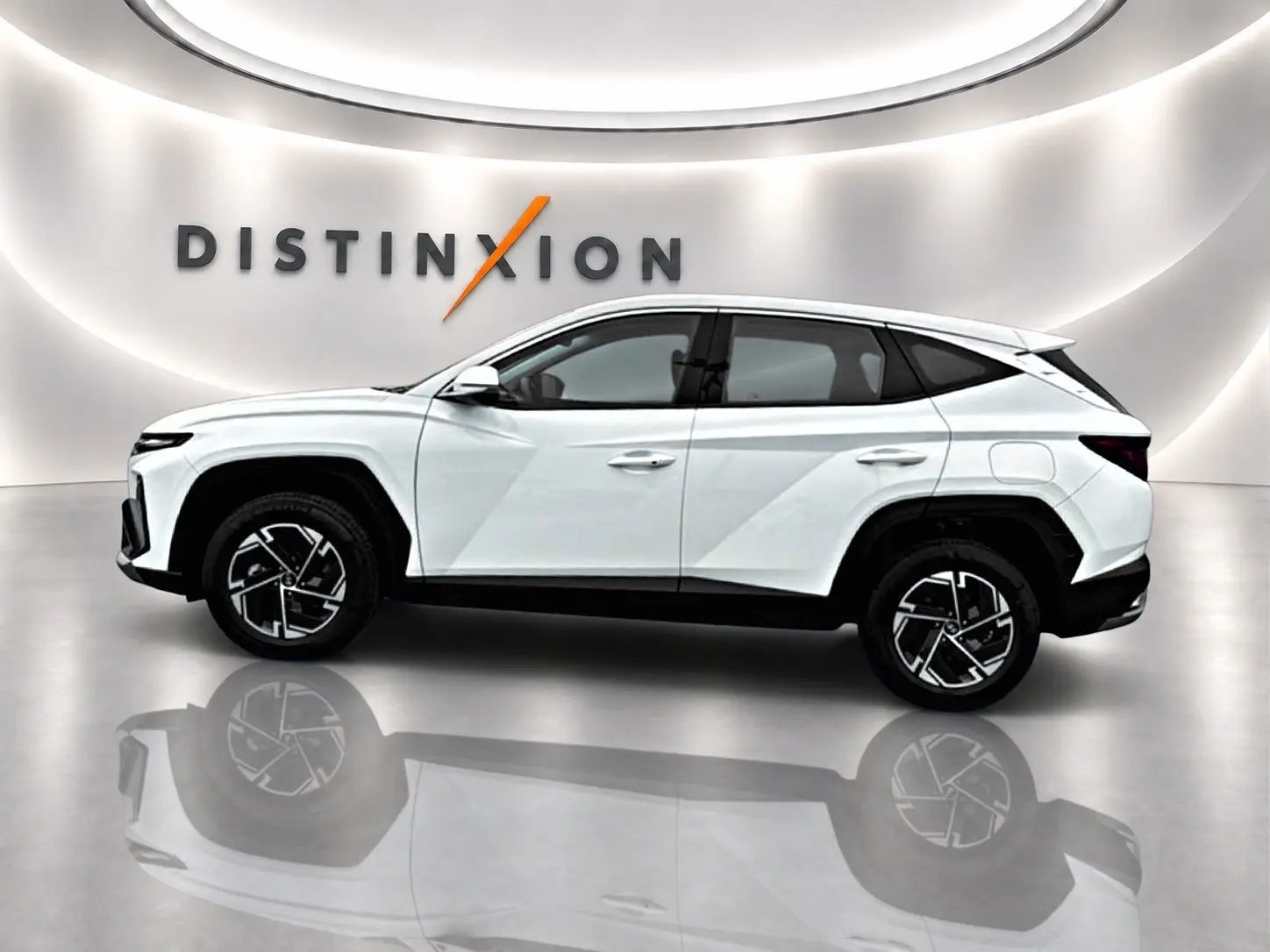 Vue de profil côté gauche du Hyundai Tucson blanc 2026 avec jantes alliage 17 pouces dans un showroom lumineux.