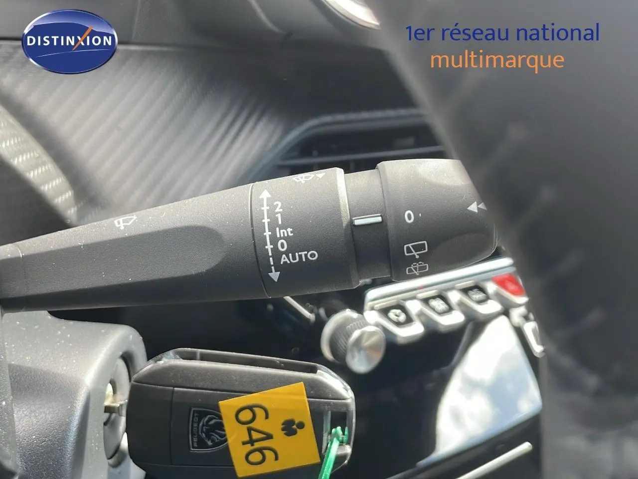 Gros plan sur la commande d'essuie-glace et la clé insérée dans le contact d'un Peugeot 2008 noir Perla Metal, intérieur moderne.