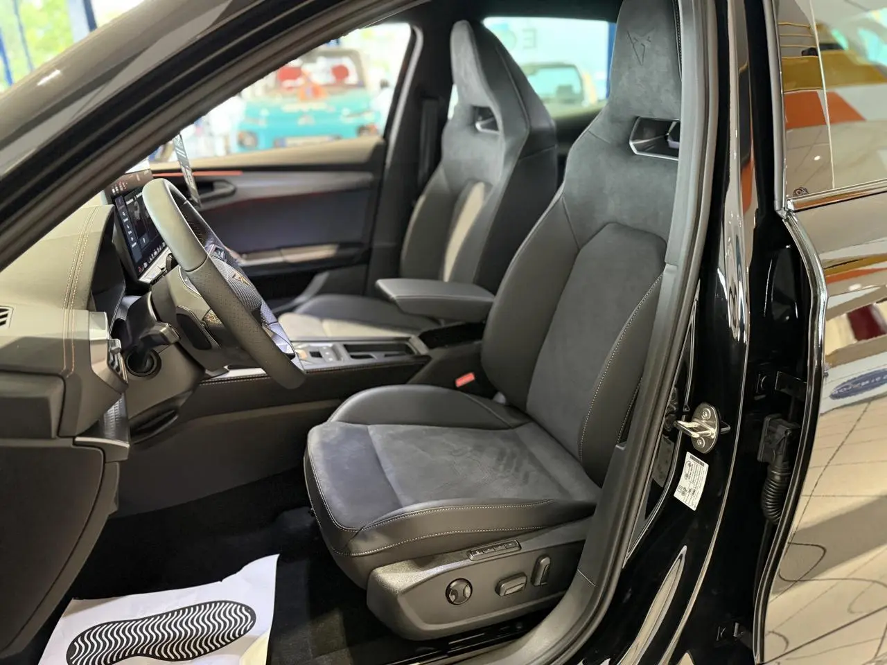 Vue intérieure côté conducteur du CUPRA Formentor noir Night, sièges baquets suédine avec surpiqûres cuivrées et logos Cupra.