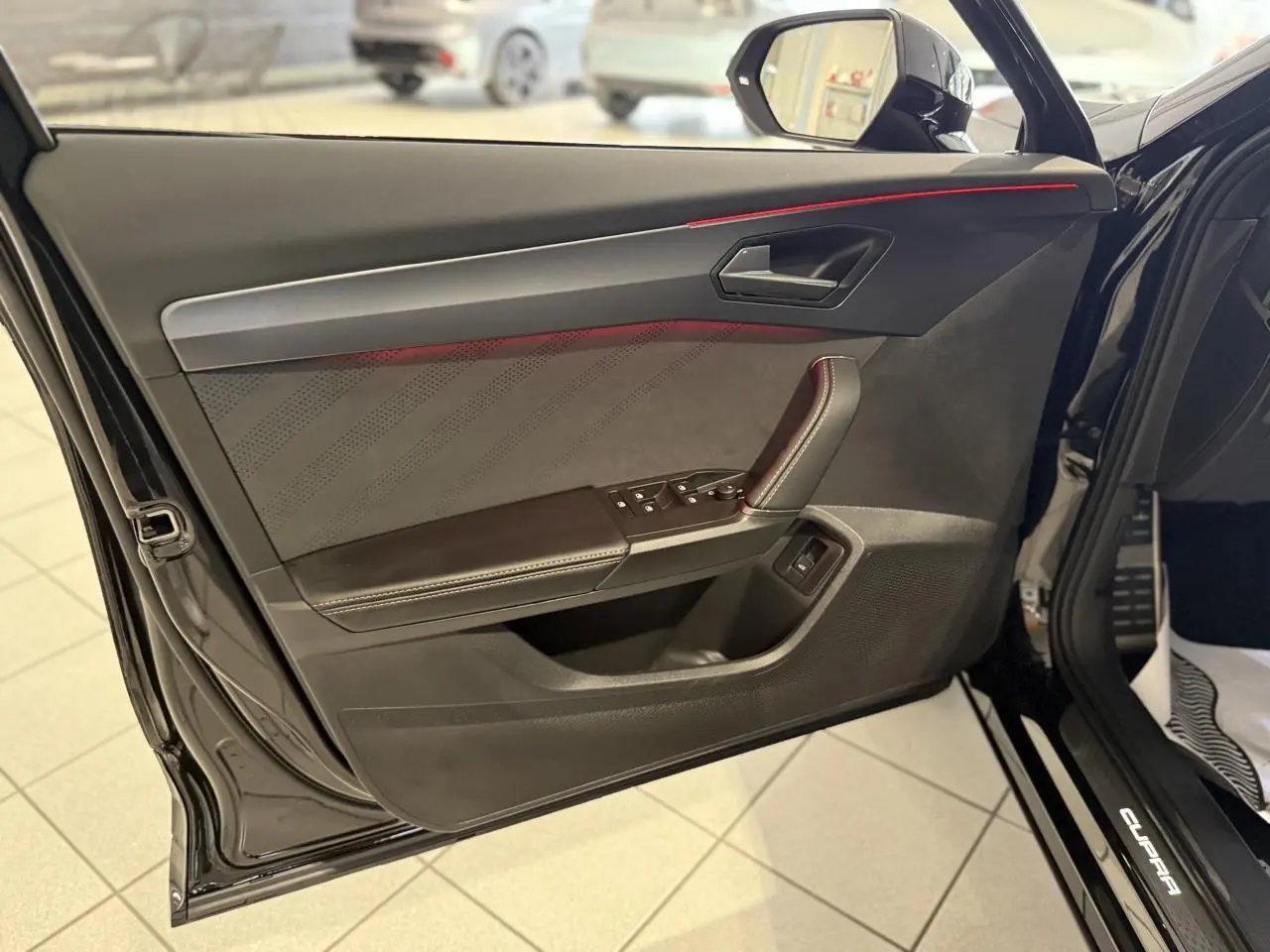 Vue rapprochée de la porte avant gauche noire Night du CUPRA Formentor 2025 avec éclairage d'ambiance rouge et finitions cuir.