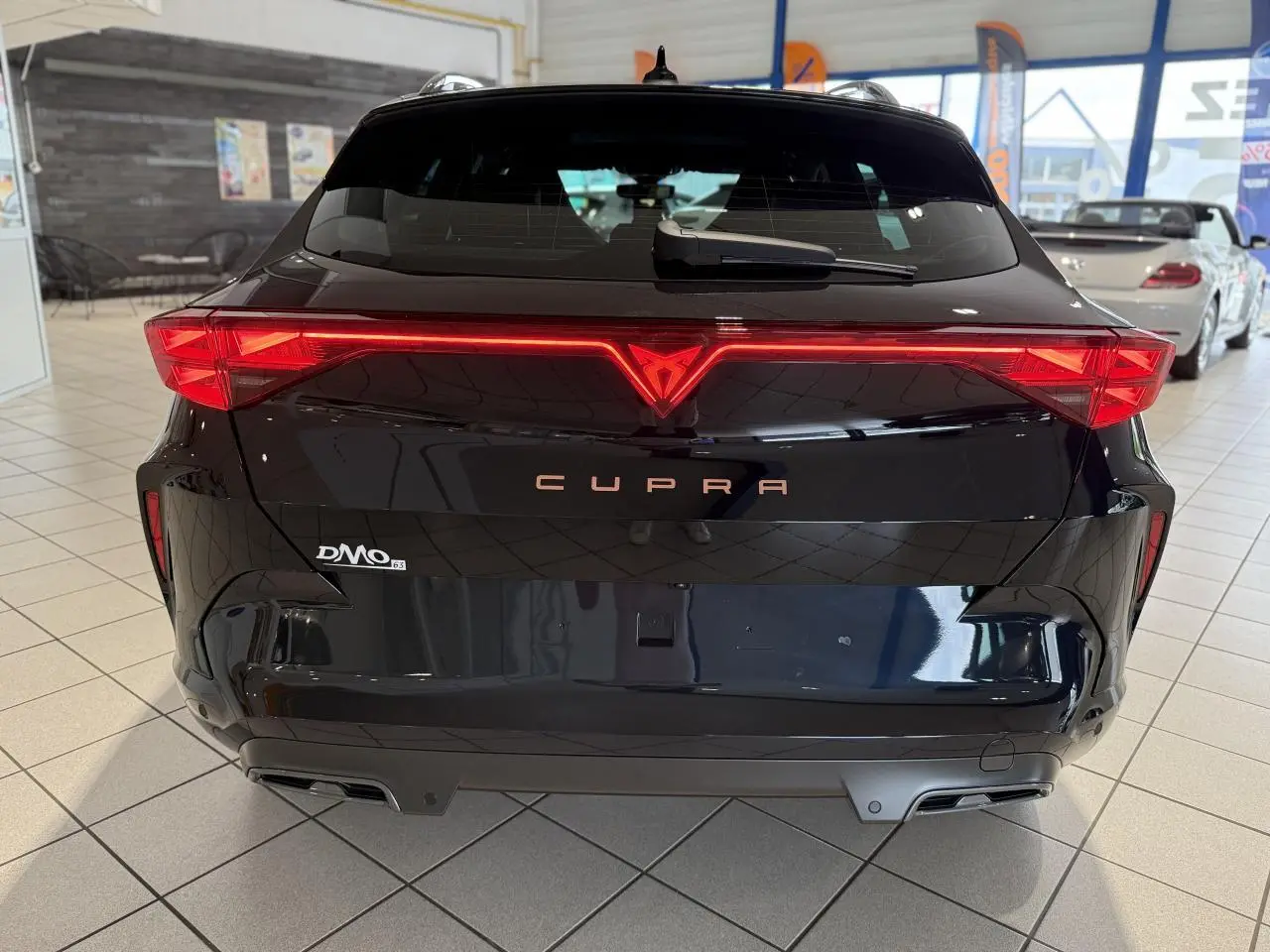 Vue arrière d'une CUPRA Formentor noire Night avec feux arrière en bandeau lumineux et double sortie d'échappement.