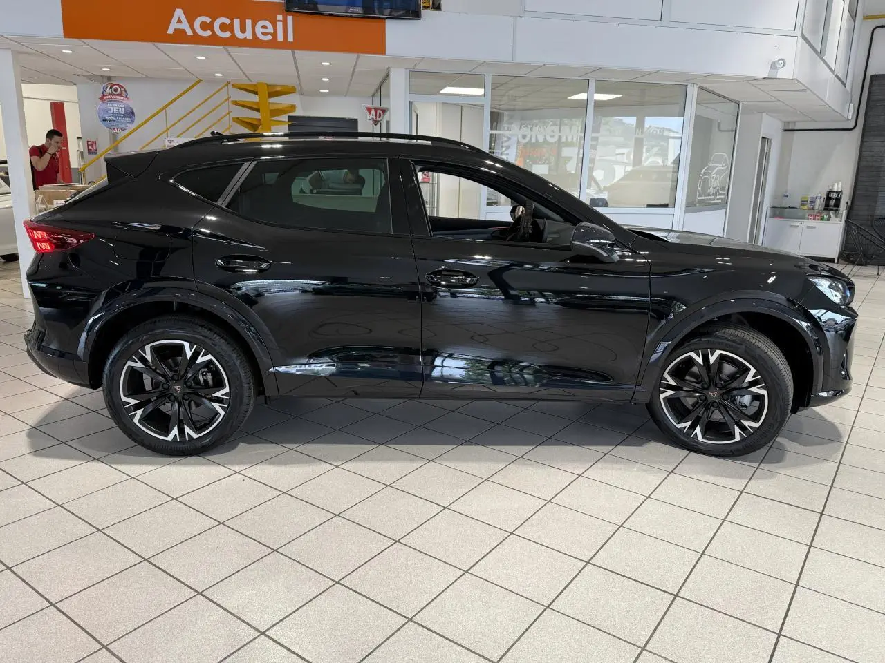 Vue profil droit du SUV CUPRA Formentor noir Night avec jantes alliage 18'' et bas de caisse noir obsidien en showroom.