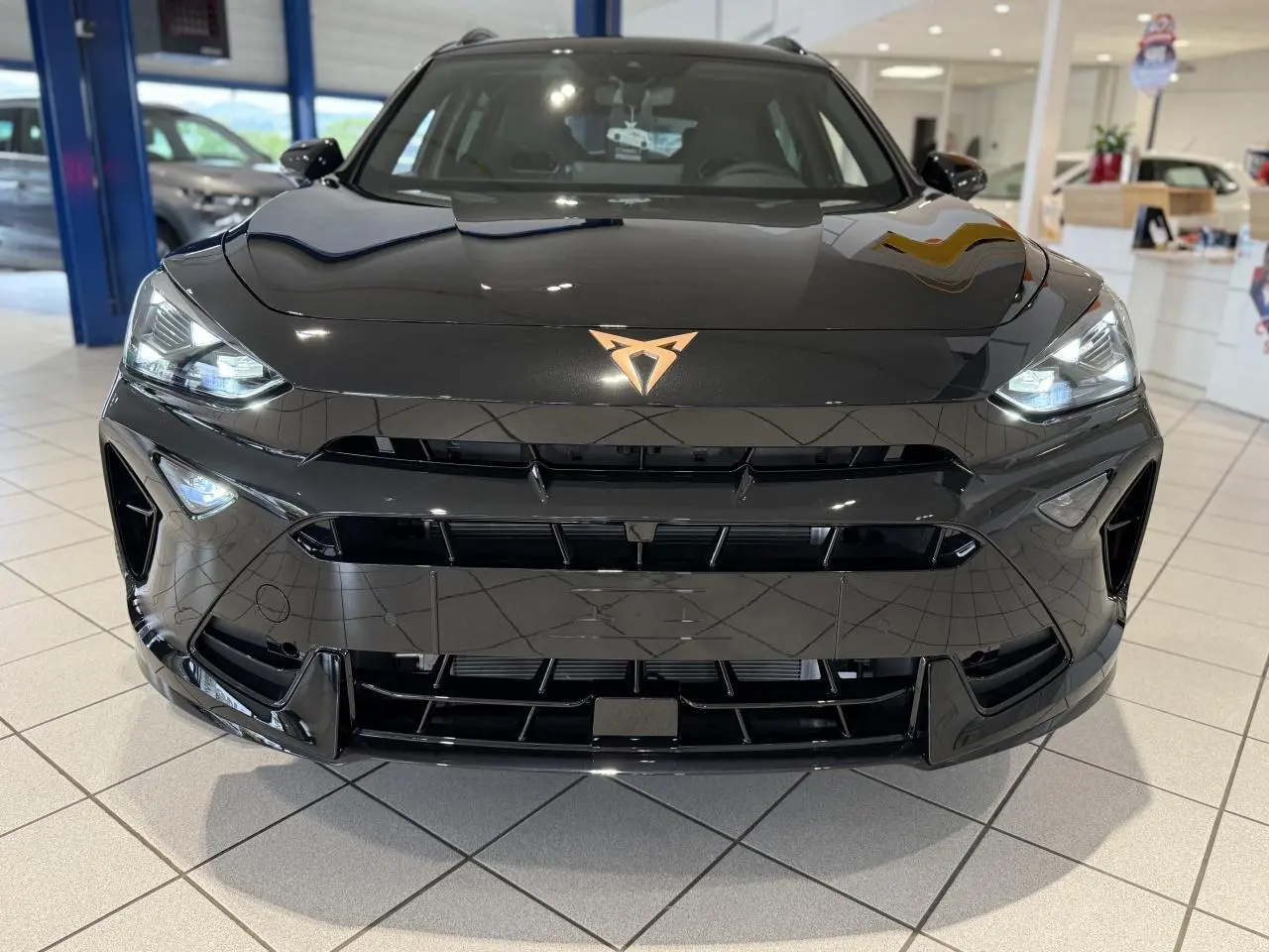 Vue frontale rapprochée du CUPRA Formentor noir Night avec logo cuivré et phares Full LED allumés.