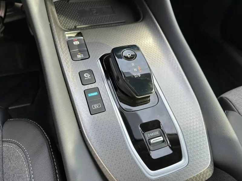Vue rapprochée de la console centrale du Nissan Qashqai Hybrid e-POWER 2025 avec levier de vitesse électronique et boutons de contrôle.