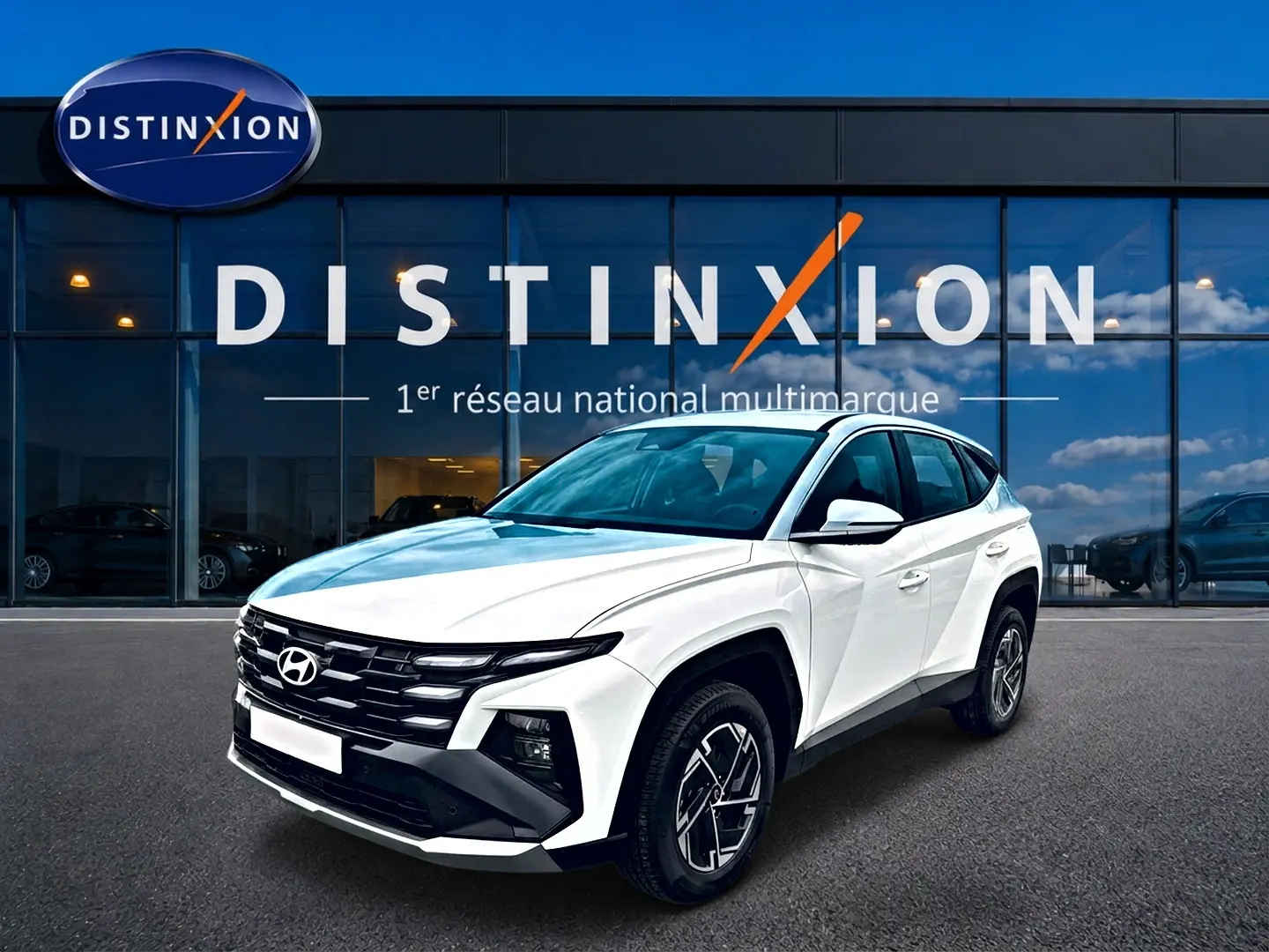 Hyundai Tucson blanc 2026 en 3/4 avant droit, avec calandre noire distinctive et jantes alliage 17 pouces.
