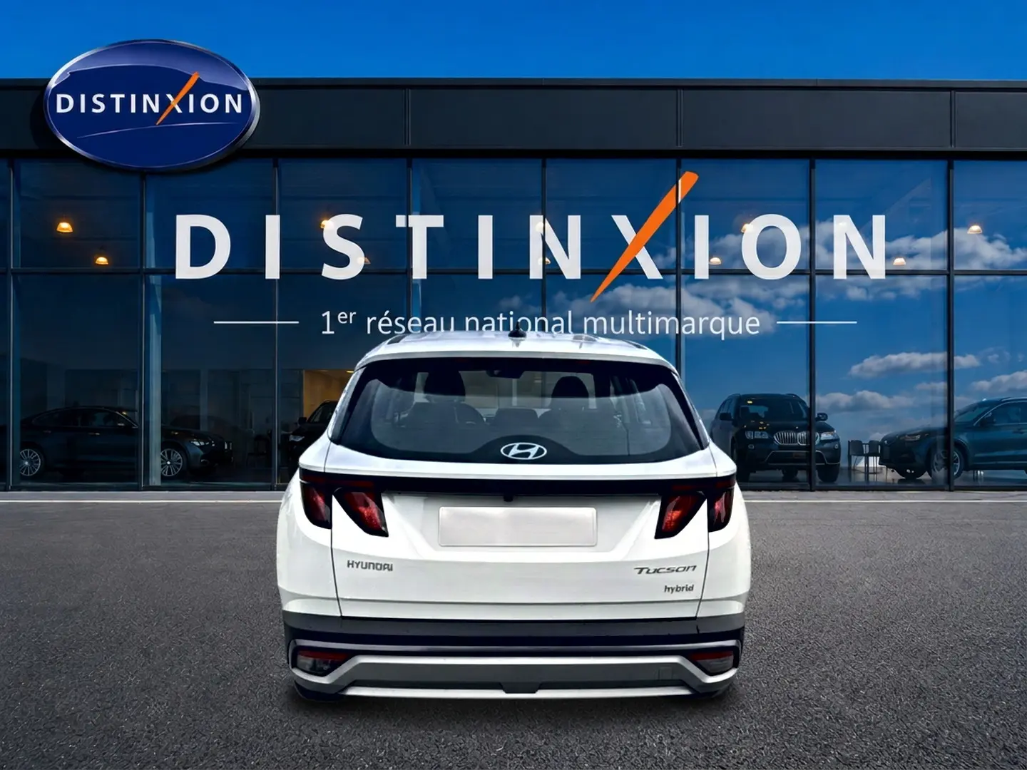 Vue arrière d'un Hyundai Tucson blanc hybride garé devant une vitrine avec logo Distinxion.