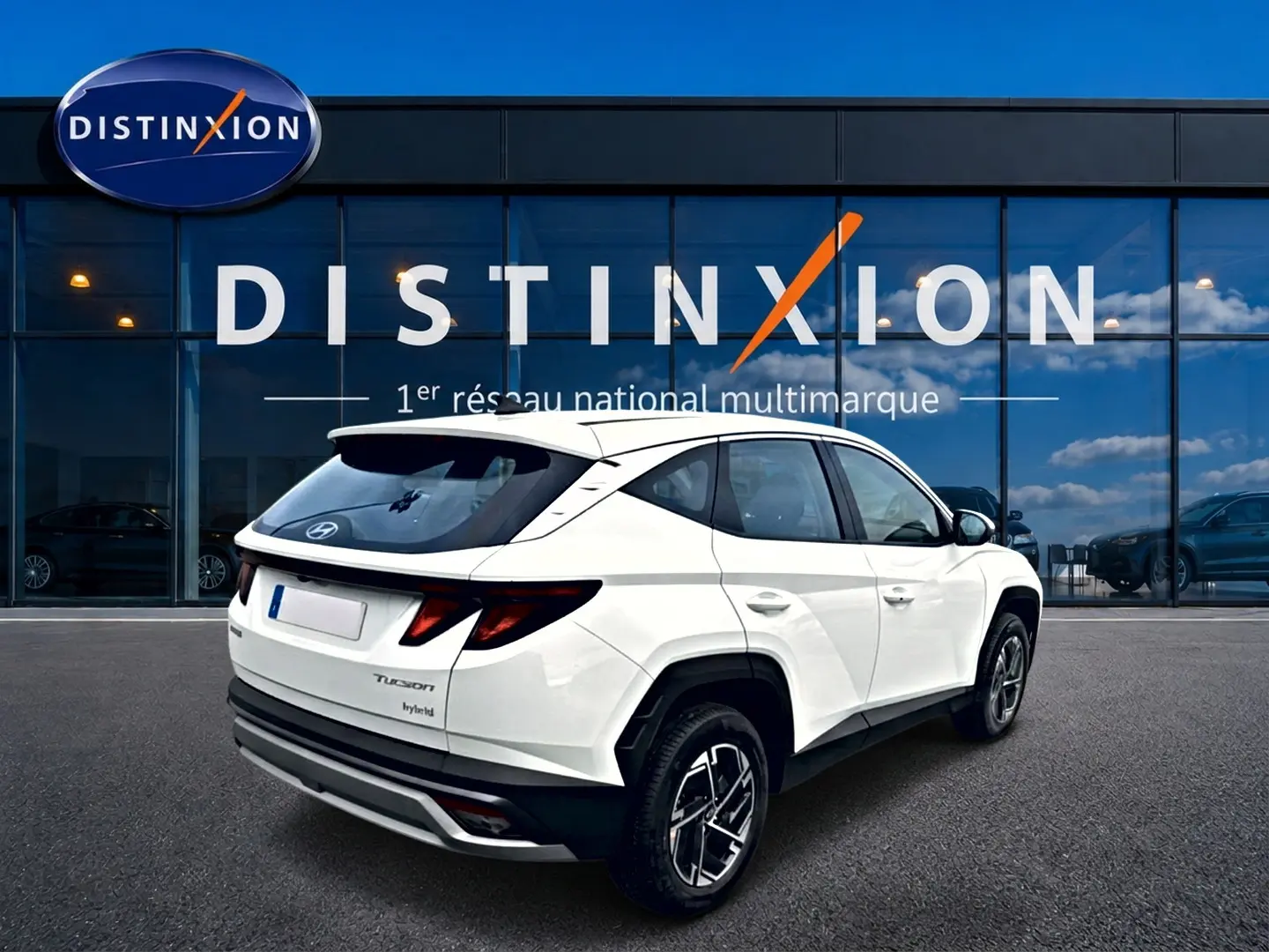 Vue 3/4 arrière droite du Hyundai Tucson blanc hybride 2026 avec jantes alliage et feux arrière LED distinctifs.