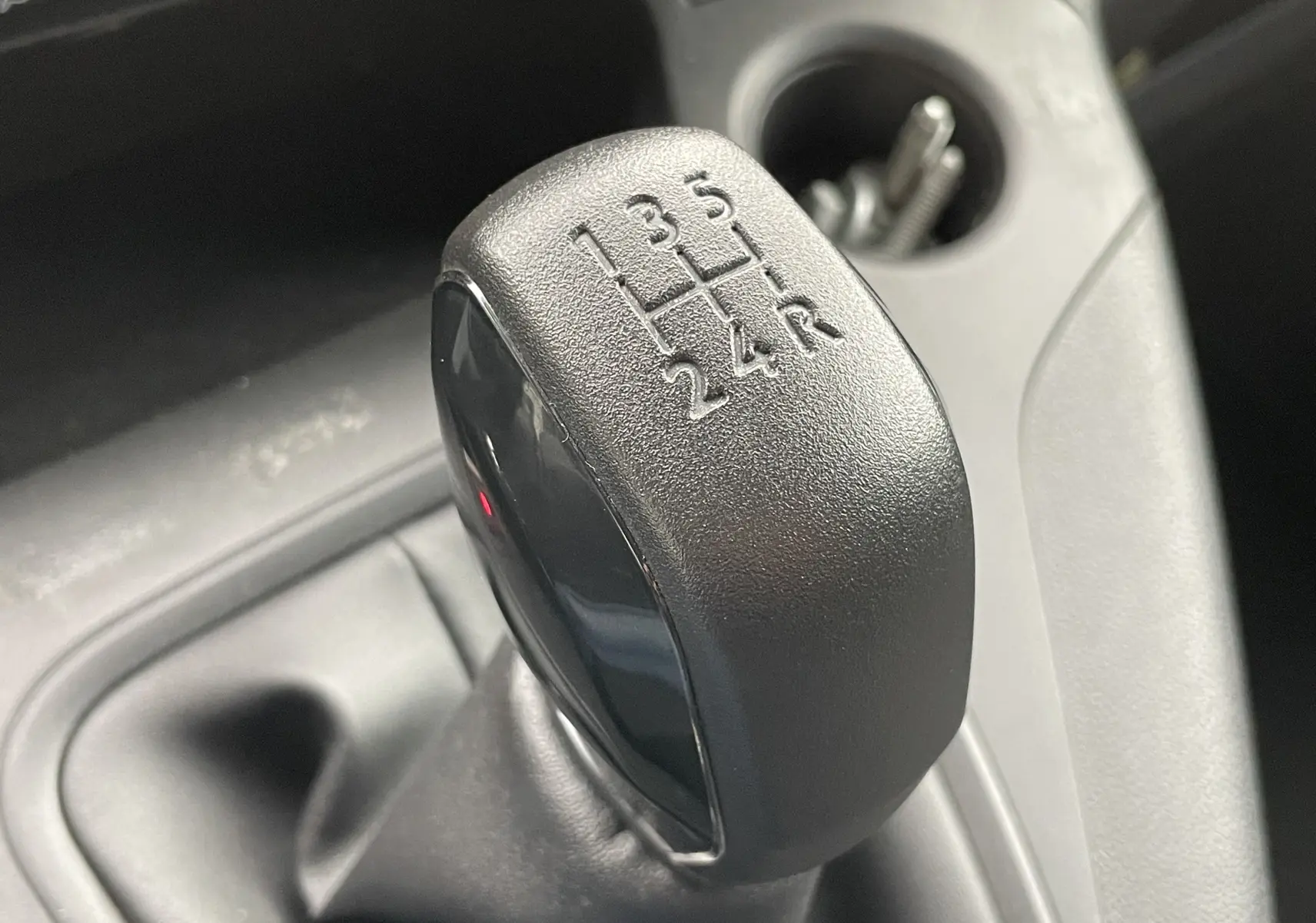 Le levier de vitesses manuel noir du Citroën Berlingo 1.5 BlueHDi 100 M, vue rapprochée de l'intérieur.