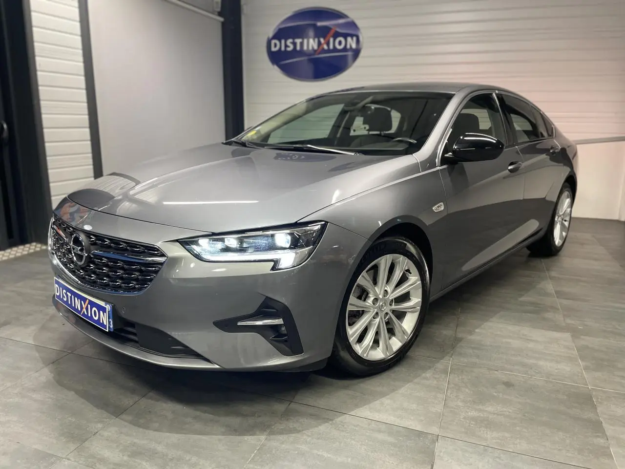 Opel Insignia Grand Sport gris clair vue 3/4 avant avec jantes alliage 17 pouces et coques de rétroviseurs noir laqué.
