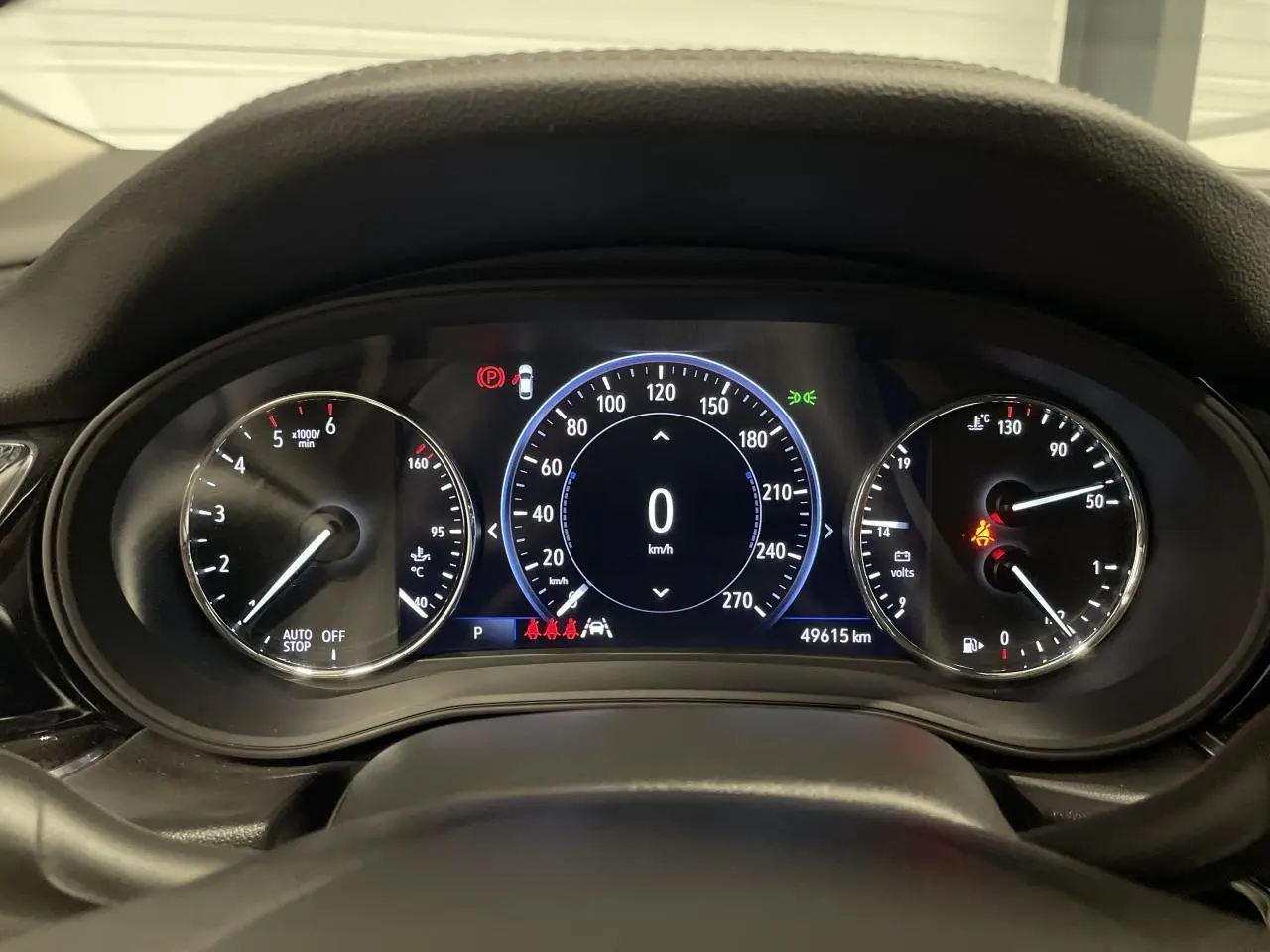 Vue rapprochée du tableau de bord numérique de l'Opel Insignia Grand Sport gris clair, affichant 0 km/h et 49 615 km.