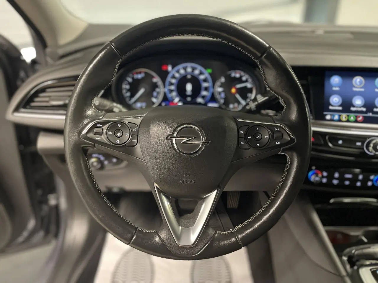Volant en cuir multifonctions de l'Opel Insignia Grand Sport 2021, avec tableau de bord et écran tactile en arrière-plan.