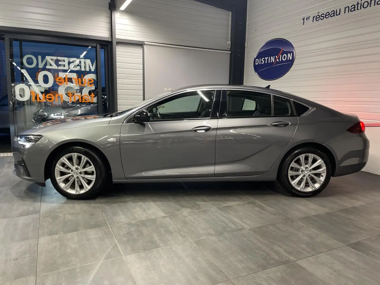 Opel Insignia Grand Sport gris clair vue de profil côté gauche dans un showroom avec jantes alliage 17 pouces.