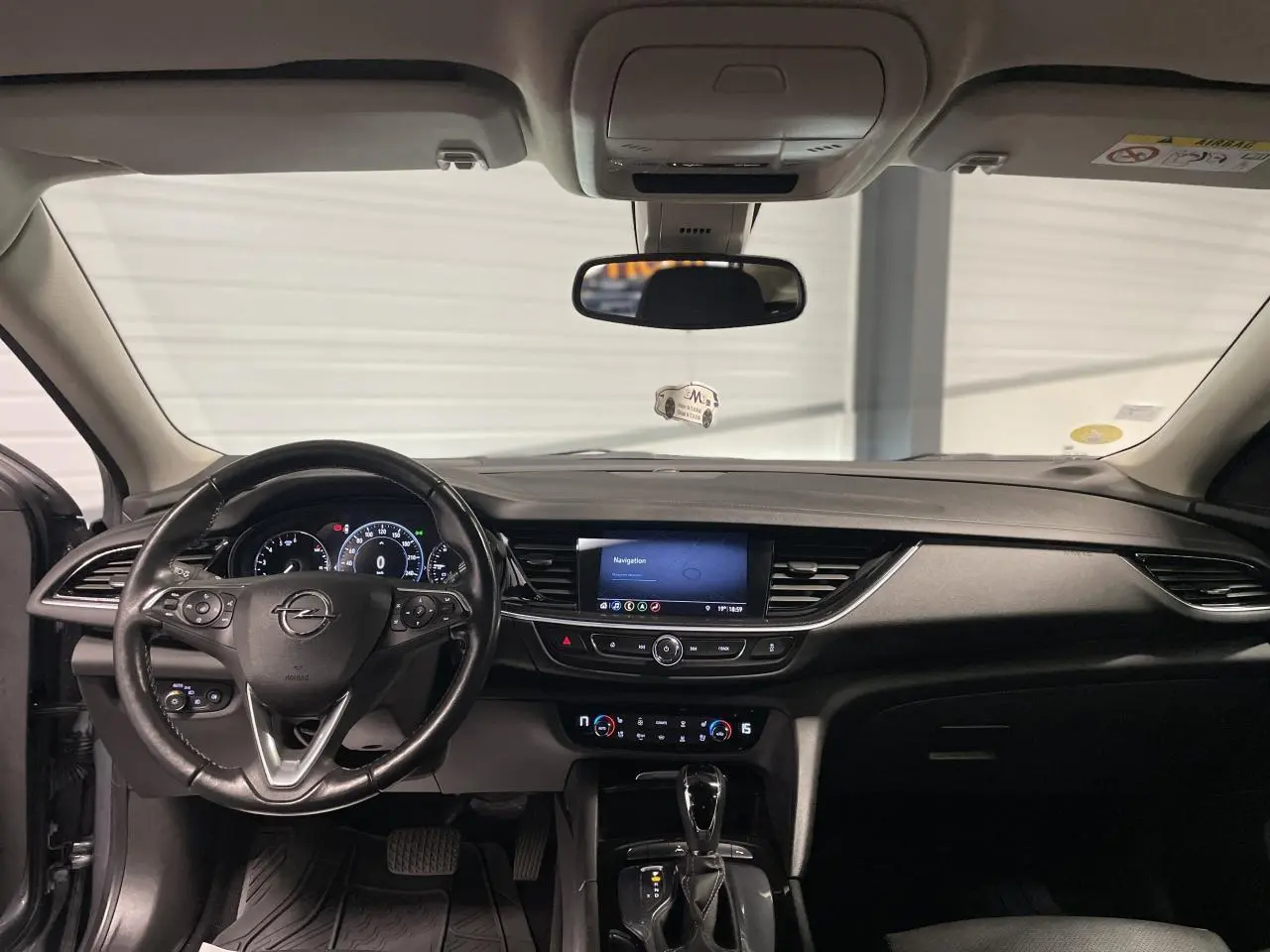 Intérieur noir de l’Opel Insignia Grand Sport 2021, vue frontale du tableau de bord avec écran tactile central et volant cuir multifonctions.