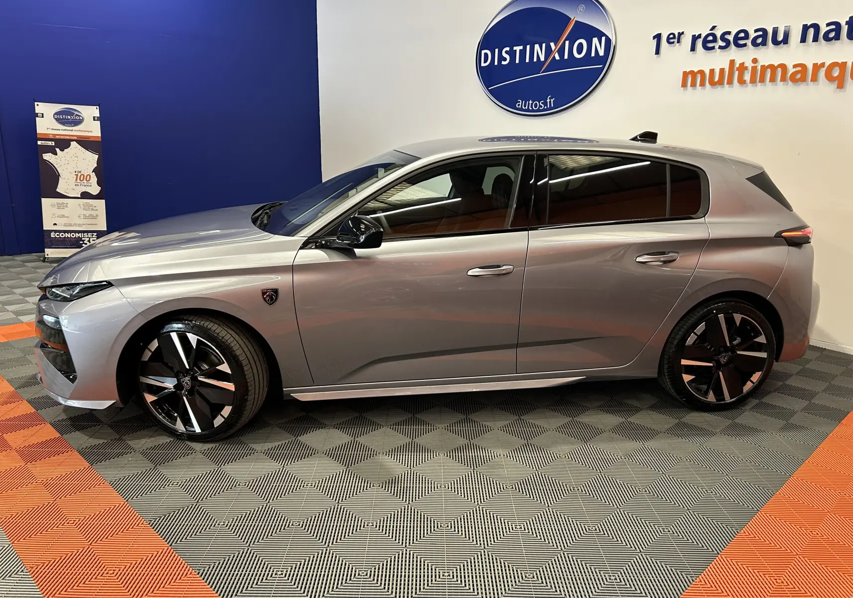Peugeot 308 gris Artense vue de profil côté gauche, avec jantes noires et détails modernes en showroom.