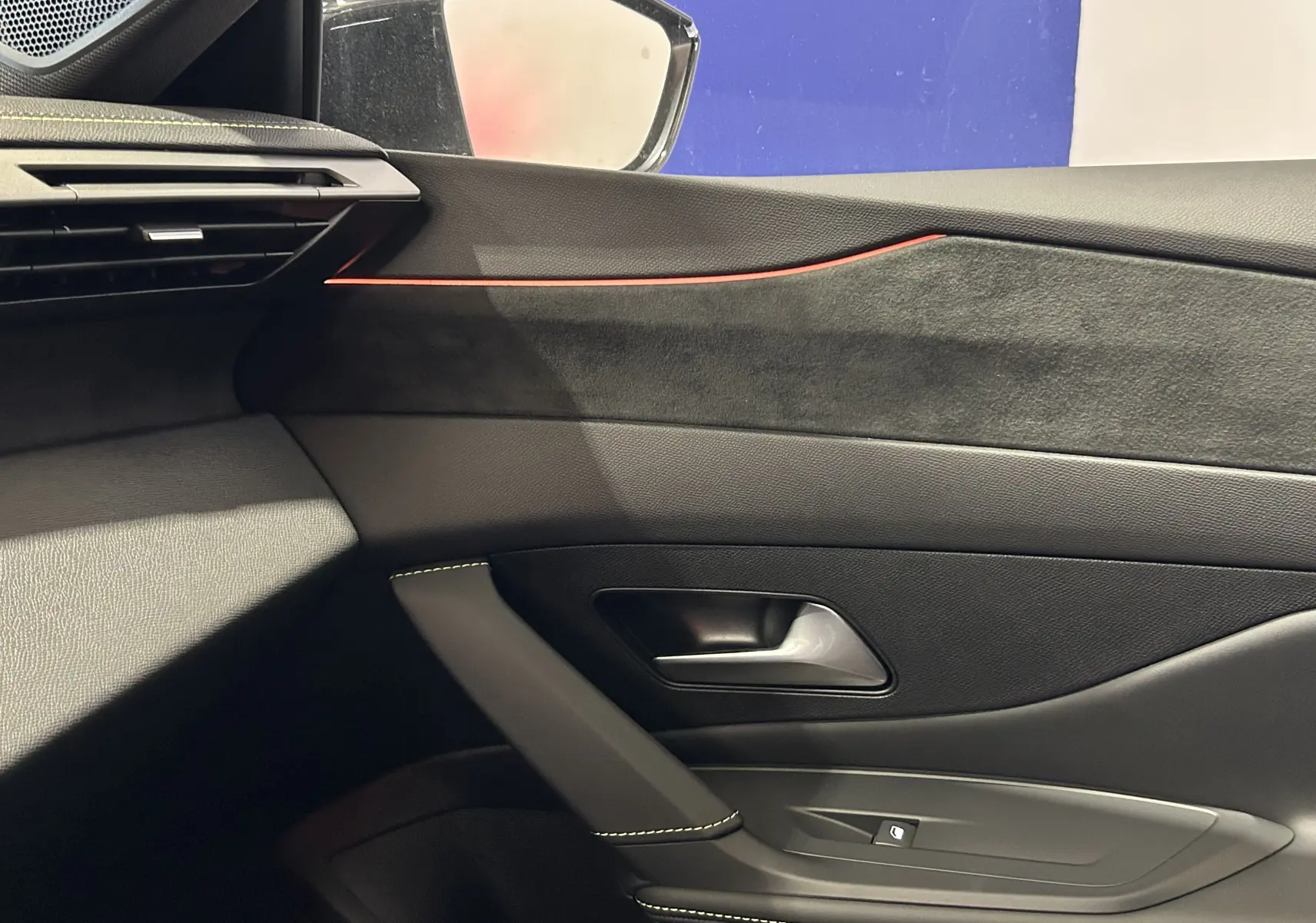 Vue intérieure côté gauche de la porte d’une Peugeot 308 gris Artense avec bandeau décoratif rouge et poignée noire.