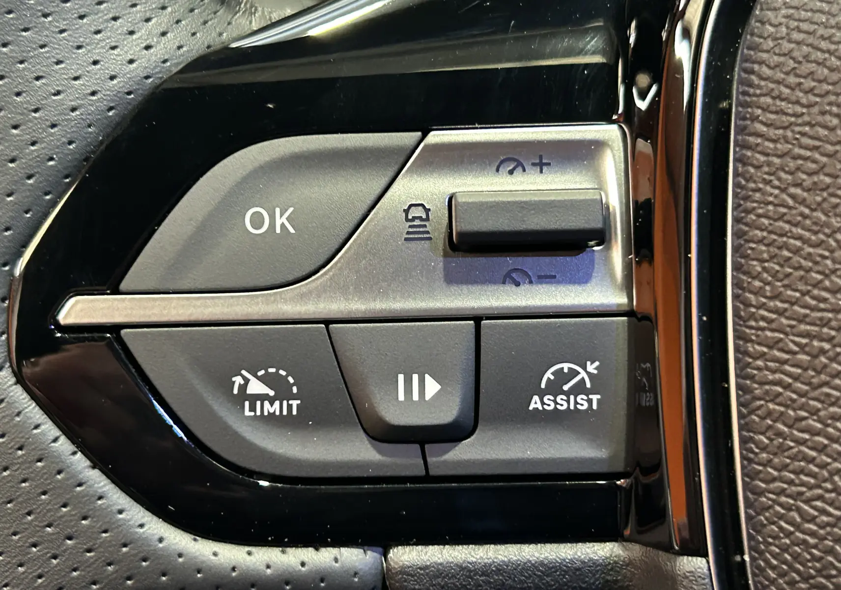 Gros plan sur les commandes de régulateur de vitesse au volant perforé noir de la Peugeot 308 GT gris Artense.