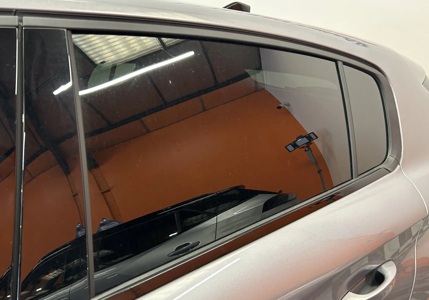 Vue latérale du côté gauche sur la porte arrière d’une Peugeot 308 gris Artense avec reflet intérieur.