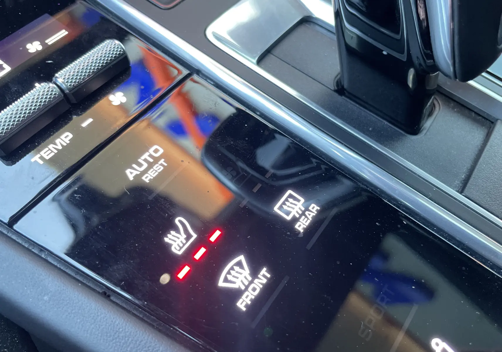 Gros plan sur la console centrale noire du Porsche Cayenne Coupé hybride, montrant les commandes de chauffage et désembuage.